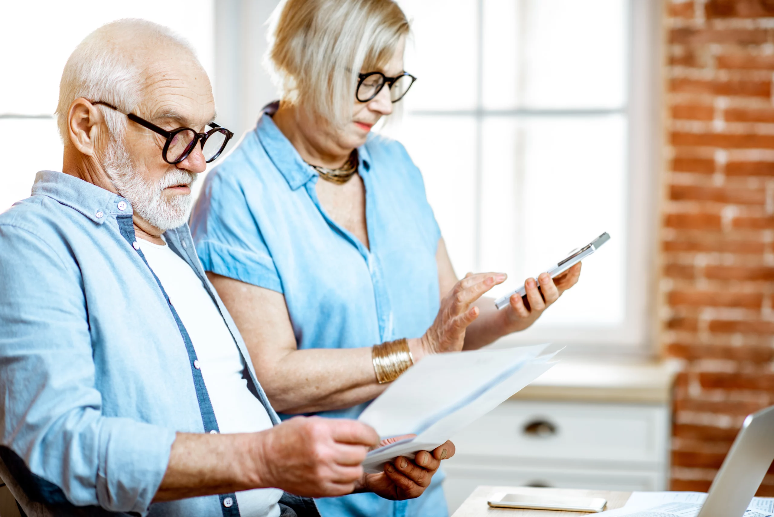 Elderly couple reviewing documents and using smartphone