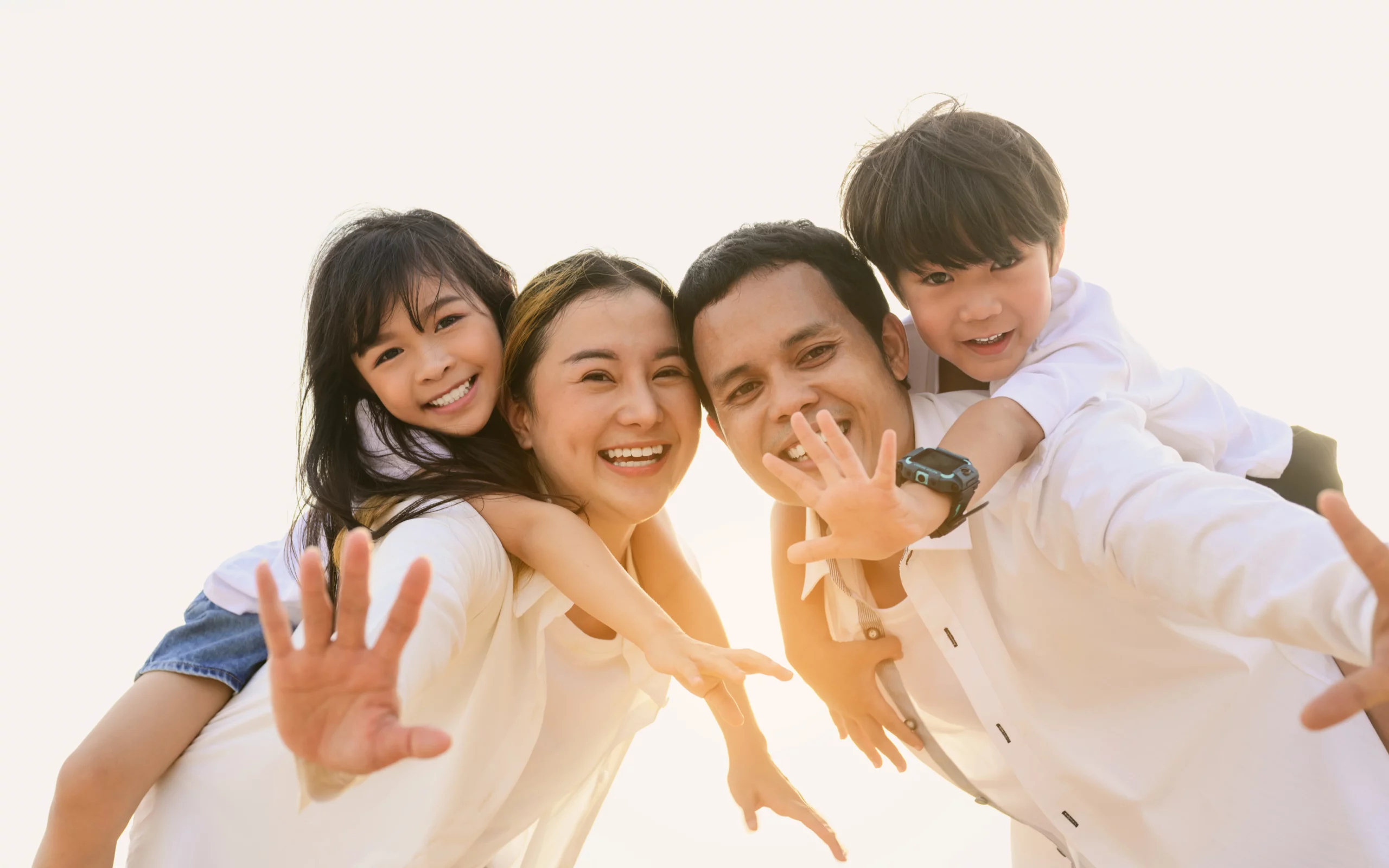 Joyful family of four at sunset, representing family unity and future planning including Medicaid planning to protect loved ones’ financial security.